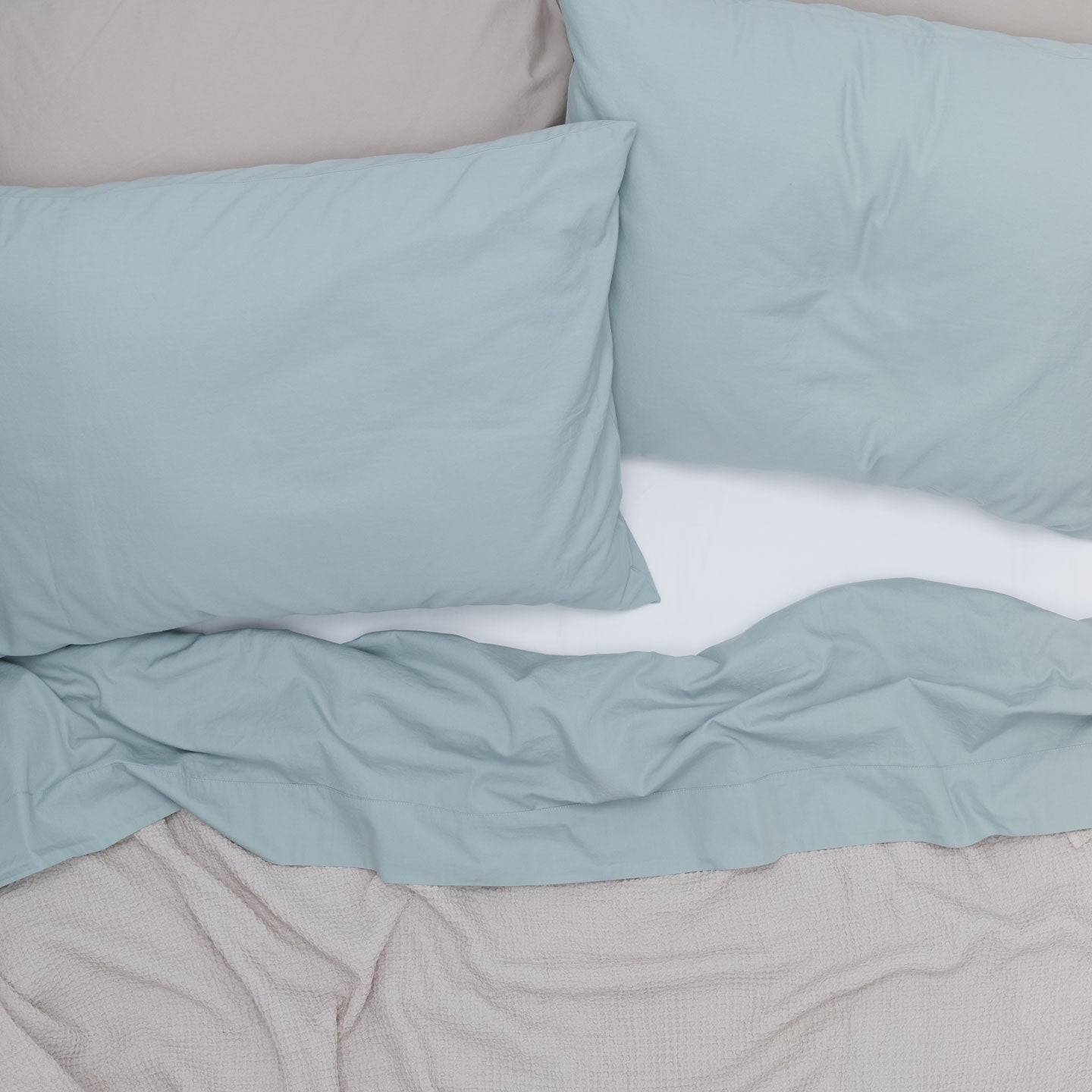 Overhead of bed made with white, blue and grey bedding.